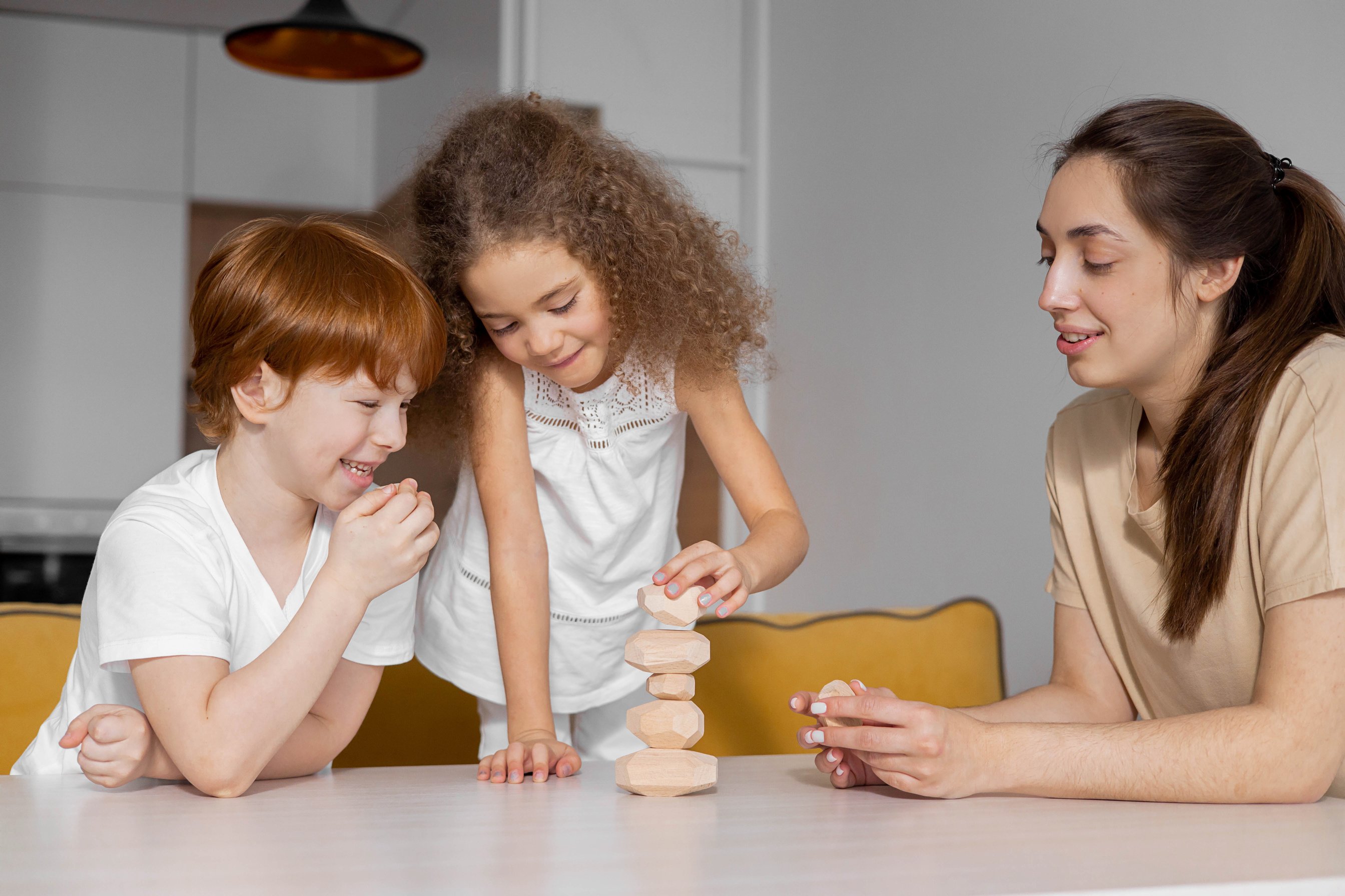 A Boy Beside a Girl Stacking Stones on a White Table